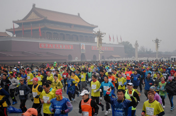 Runners take part in the 34th Beijing International Marathon which began at Tiananmen Square in Beijing on October 19, 2014, with many of the tens of thousands of participants wearing face masks, as the 42-kilometer course ended at the Olympic Park. (AFP Photo/China Out)