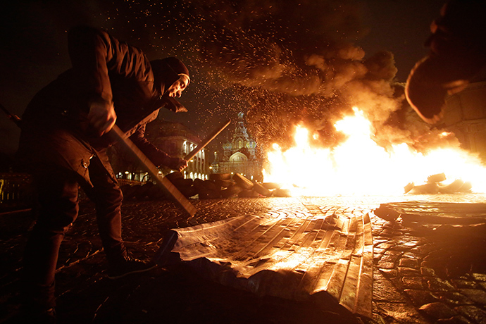 Artist Pyotr Pavlensky drums with sticks as tyres burn during a performance called "Freedom", in support of Ukrainian anti-government protesters who held rallies in Maidan Nezalezhnosti or Independence Square in Kiev, in front of the Church of the Saviour on Spilled Blood in central St. Petersburg February 23, 2014 (Reuters / Maxim Zmeyev)