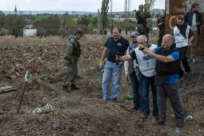 OSCE observers take pictures at the site where rebels say is a mass grave with five bodies, in the town of Nizhnaya Krinka, eastern Ukraine, September 23, 2014 (Reuters / Marko Djurica)
