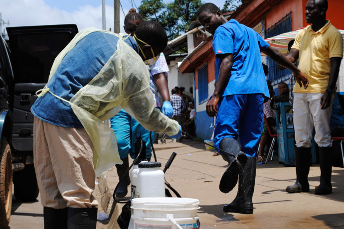 A health worker sprays a colleague's boots with chlorine disinfectant in Monrovia October 20, 2014. (Reuters / James Giahyue)