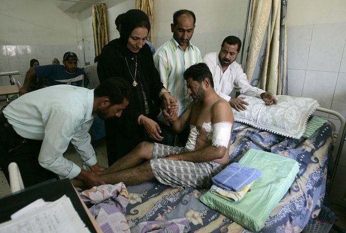 A man who was wounded in a shooting attack by the security guards of Blackwater firm on Sunday, is helped by his relatives in a hospital in Baghdad (Reuters//Ceerwan Aziz)
