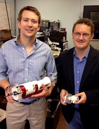 David Comber, left, and Eric Barth holding major components of their surgical robot. (Heidi Hall / Vanderbilt)