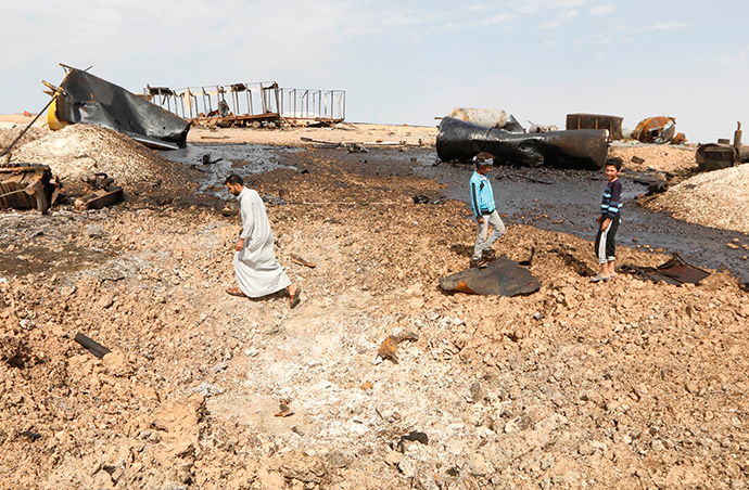 Locals inspect damage at an oil refinery that was targeted by what activists said were U.S.-led air strikes at al-Khaboura village, near the Syrian town of Tel Abyad of Raqqa governate, October 2, 2014 (Reuters / Stringer)