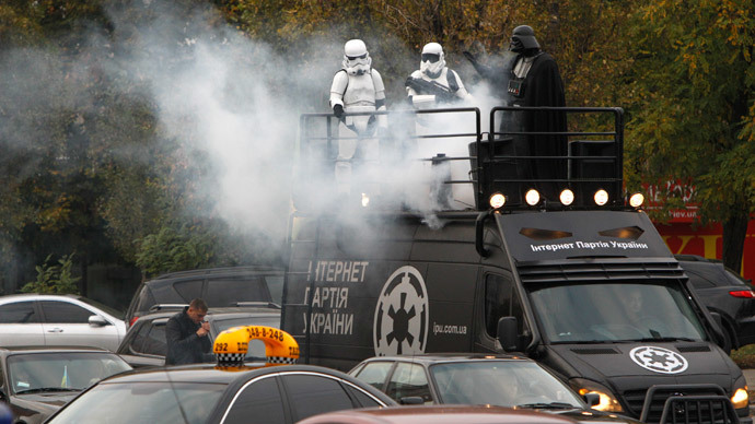 A candidate (R), presenting himself in the character of "Star Wars" villain Darth Vader and representing the Internet Party of Ukraine which runs for parliament, stands on the top a vehicle as he leaves after a meeting with his supporters and voters in Kiev, October 22, 2014.(Reuters / Valentyn Ogirenko)