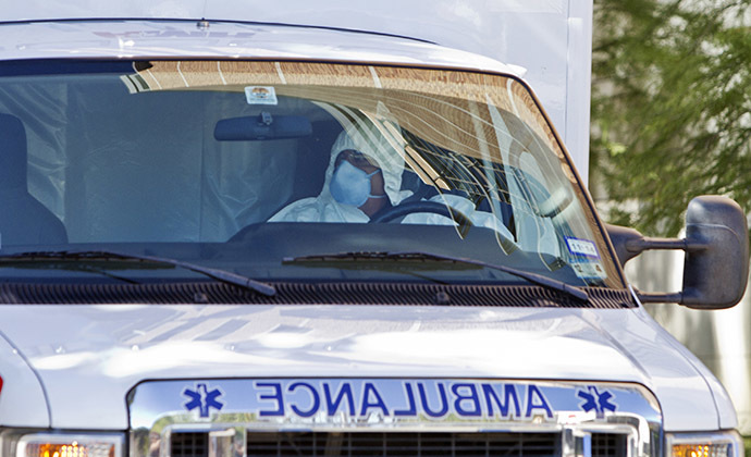 An ambulance driver wearing a protective suit escorts Amber Joy Vinson (not shown), the second health worker to be infected with the Ebola virus at Texas Health Presbyterian Hospital to the airport in Dallas, Texas October 15, 2014. (Reuters/Jaime R. Carrero)