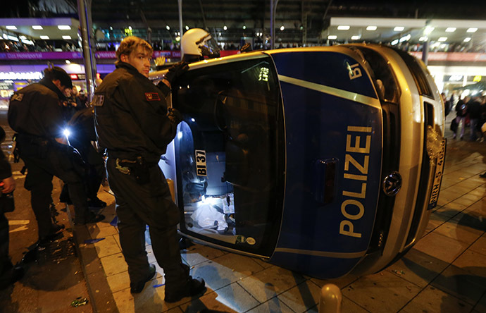 German riot police officers use torches to look for their personal belongings in an overturned police van following a demonstration by German far-right groups in Cologne October 26, 2014. (Reuters/Wolfgang Rattay)