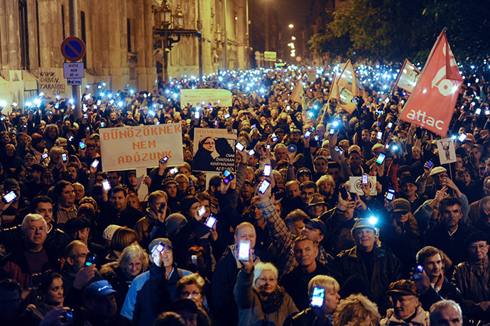 Hungarian citizens lift their mobile phones to protest against the goverment's new tax plan for the introduction of the internet tax next year in Budapest downtown on October 26, 2014. (AFP Photo/Attila Kisbenedek)