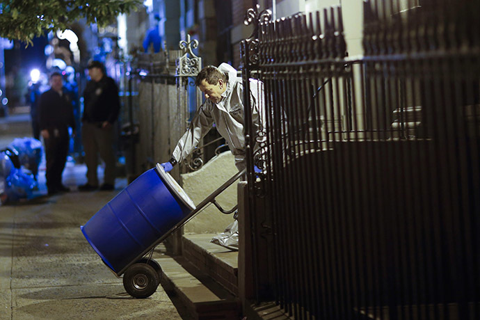 A member of a cleaning crew with "Bio Recovery Corporation" wearing personal protective equipment (PPE) pushes a barrel to be loaded in a truck of Centers for Disease Control and Prevention (CDC) after cleaning the apartment where Dr. Craig Spencer lives in New York October 24, 2014. (Reuters/Eduardo Munoz)