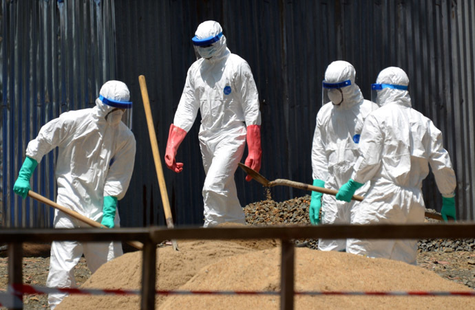Health workers from the Liberian Red Cross wear protective gear as they shovel sand which will be used to absorb fluids emitted from the bodies of Ebola victims in front of the ELWA 2 Ebola management center in Monrovia on October 23, 2014. (AFP Photo)