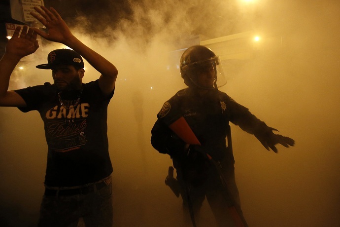 A reveller raises his arms after being ordered to disperse by the police during a street celebration in San Francisco, California (Reuters/Stephen Lam)