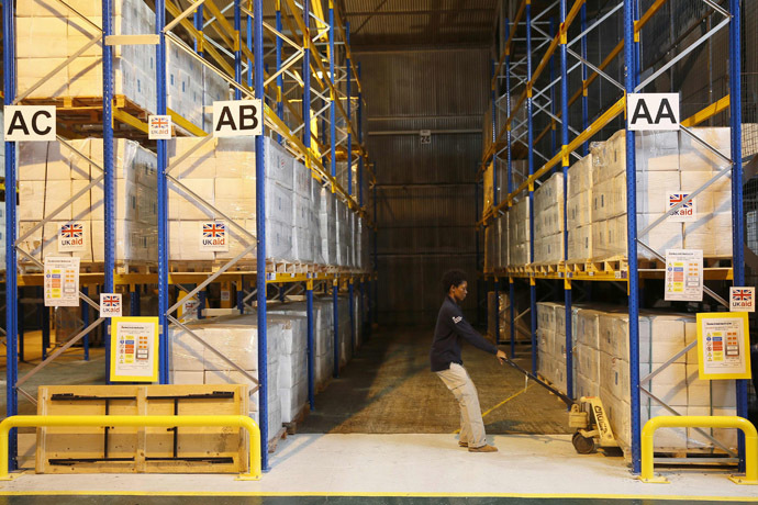 A Department for International Development (DfID) worker moves boxes containing kitchen sets at a UK Aid Disaster Response Centre where humanitarian supplies are being collected to be airlifted to Iraq at Cotswold Airport near the village of Kemble, Gloucestershire, southern England on August 14, 2014. (AFP Photo/Stefan Wermuth)