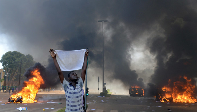 A protester holds a white cloth as cars and documents burn outside the parliament in Ouagadougou on October 30, 2014. (AFP Photo/Issouf Sango) 