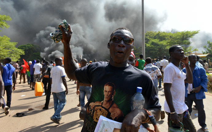Protesters stand outside the parliament in Ouagadougou on October 30, 2014 as cars and documents burn outside. (AFP Photo/Issouf Sango)