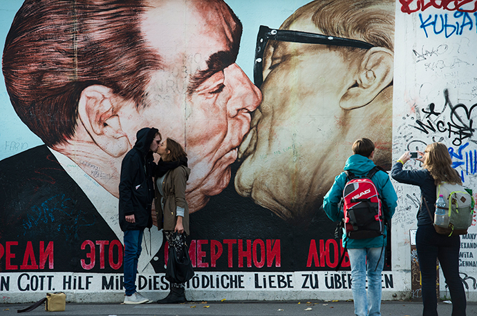 Tourists mimic a kiss in front of a likeness of that between then-Soviet leader Leonid Brezhnev (L) and East Germany's Erich Honecker at the East Side Gallery, a stretch of the Berlin wall, in Berlin (AFP Photo / John Macdougall)