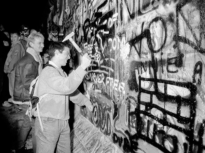 A man hammers a section of the Berlin Wall near the Brandenburg Gate after the border opening was announced, November 9, 1989. (Reuters / Fabrizio Bensch)