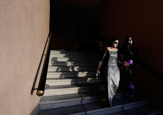 Women with faces painted to look like the popular Mexican figure called "Catrina" walk down a staircase in Zapopan (Reuters / Alejandro Acosta)
