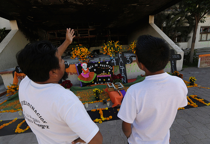 People look at an installation of a skeleton, skulls and Cempasuchil marigold petals, part of an altar assembled by residents to celebrate the Day of the Dead, outside the Municipal Palace in Iguala, in the southwestern state of Guerrero (Reuters / Henry Romero)