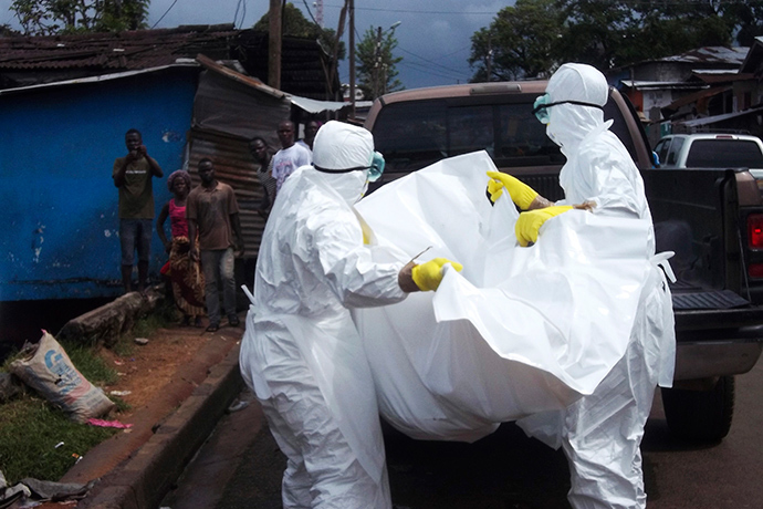 Health workers remove the body of a man believed to have died from the Ebola virus at a street in Monrovia, Liberia, October 27, 2014 (Reuters / James Giahyue)