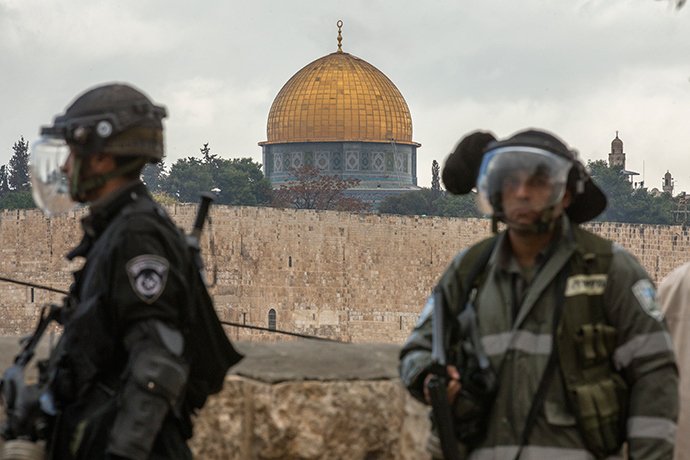 Israeli security forces keep watch backdropped by the Dome of the Rock mosque during Friday noon prayers in the east Jerusalem neighbourhood of Ras al-Amud on October 31, 2014, following restrictions by Israeli police to allow entry to men only above 50-year-old wanting to access the Al-Aqsa Mosque compound. Israeli police deployed heavily around Jerusalem's flashpoint Al-Aqsa mosque compound as it reopened today for Muslim prayers after a rare closure during clashes over the killing of a Palestinian by security forces (AFP Photo / Jack Guez)