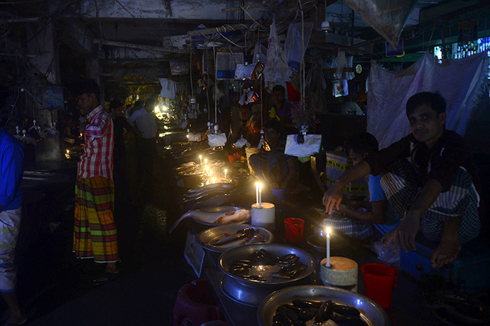 Bangladesh fishmongers light their fish stalls with candles during a power blackout in Dhaka on November 1, 2014 (AFP Photo / Munir uz Zaman)