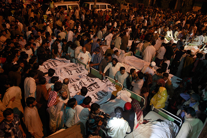 Pakistani relatives gather beside the covered bodies of victims who were killed in suicide bomb attack in Wagha border near Lahore November 2, 2014 (Reuters / Mohsin Raza)