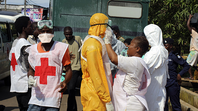 A health worker fixes another health worker's protective suit in the Aberdeen district of Freetown, Sierra Leone, October 14, 2014. (Reuters/Josephus Olu-Mammah)