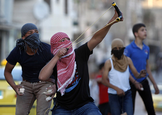A Palestinian protester uses a slingshot to hurl a stone at Israeli troops during clashes following a protest calling for the release of Palestinian prisoners from Israeli jails, in the West Bank city of Hebron May 2, 2014. (Reuters/ Mussa Qawasma)