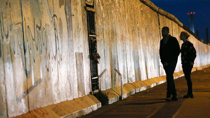 People are silhouetted as they walk in front of sections at the East Side Gallery, the largest remaining part of the former Berlin Wall, in Berlin.(Reuters / Fabrizio Bensch)