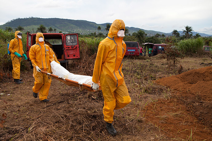 Volunteers in protective suit carry for burial the body of a person who died from Ebola in Waterloo, some 30 kilometers southeast of Freetown, on October 7, 2014.(AFP Photo/Florian Plaucheur)