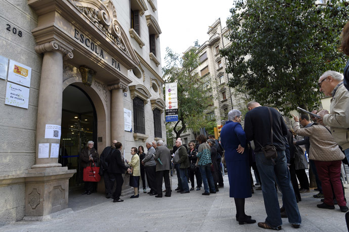 People wait on November 9, 2014 outside a school in Barcelona to vote in a symbolic ballot on whether to break away as an independent state, defying fierce challenges by the Spanish government. (AFP Photo/Lluis Gene)