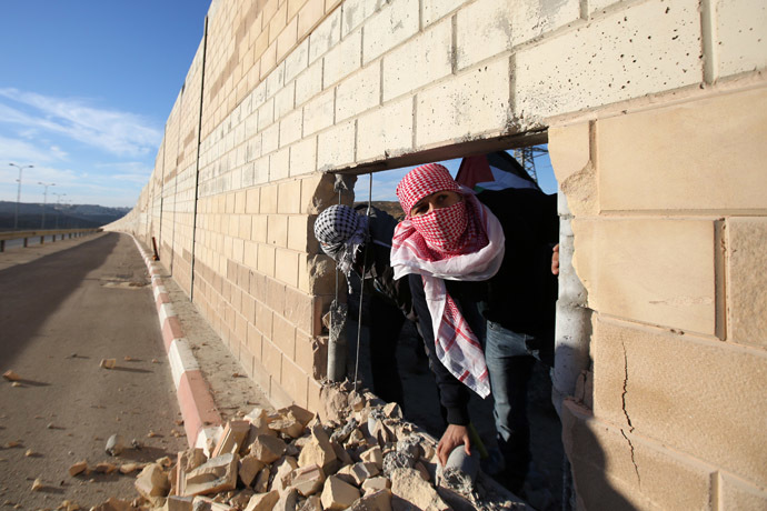 Palestinian youths appear through a hole they dug in the controversial Israeli separation wall in the West Bank village of Bir Nabala -between Jerusalem and Ramallah- on November 8, 2014 as celebrations today mark 25 years since the fall of the Berlin Wall. (AFP Photo)