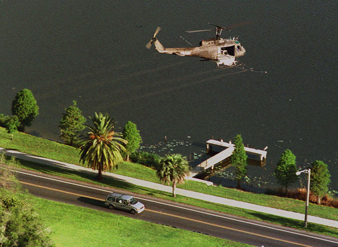 A Huey helicopter sprays malathion on an area near where Mediterranean fruit flies were found in Lakeland, June 21 as motorists pass below. (Reuters)