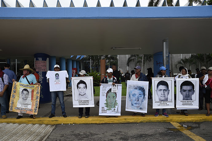 Demonstrators hold pictures of some of the 43 missing students as they block the entrances of the airport during clashes with riot police that erupted during a protest against their suspected massacre, in Acapulco, in the Mexican state of Guerrero State, on November 10, 2014. (AFP Photo/Ronaldo Schemidt)