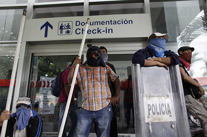 Masked protesters stand outside a building of the airport while blocking the access during a protest in reprisal for the apparent killing of 43 trainee teachers, in Acapulco November 10, 2014. (Reuters/Daniel Becerril)