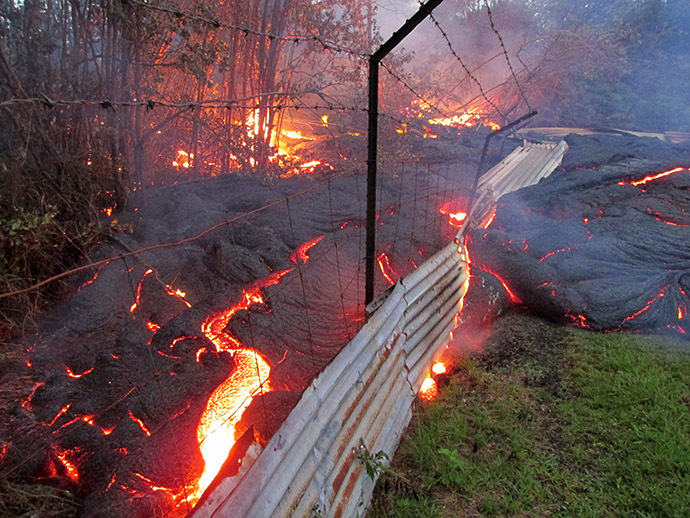 This image provided by the US Geological Survey (USGS) shows lava from the Kilauea volcano in Pahoa, Hawaii from the lobe that was active in the forest below the Pahoa cemetery overcomes a fence marking private property late on the afternoon of October 31, 2014. (AFP Photo/US Geological Survey)