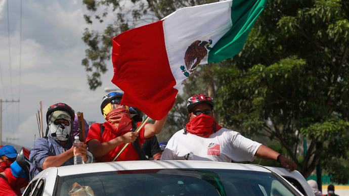 Masked members of CETEG (State Coordinator of Teachers of Guerrero teacher's union), with the Mexican national flag, gather outside the comptroller's office of the Secretary of the Department of Education in Guerrero, in Chilpancingo, November 12, 2014.(Reuters / Jorge Dan Lopez)