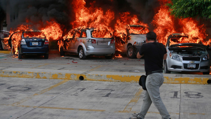 A news photographer take pictures of cars set alight by CETEG (State Coordinator of Teachers of Guerrero teacher's union) members at a City Congress parking lot in Chilpancingo, November 12, 2014.(Reuters / Jorge Dan Lopez)