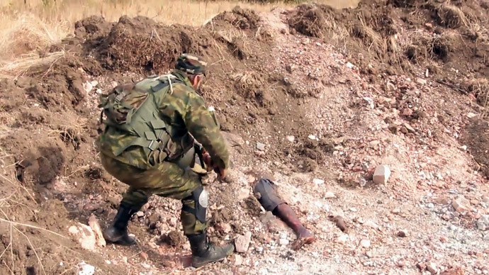 A Donetsk People's Republic militiaman is at the site of the graves of peaceful residents discovered near Mine 22 "Kommunar" outside Donetsk (stills from video courtesy of the Ruptly international news agency)