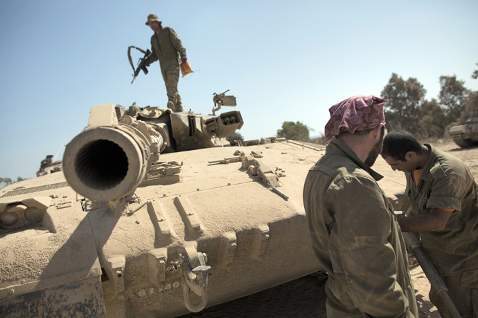 Israeli soldiers works on a Merkava tank at an army deployment point near the Israeli-Gaza border (AFP Photo / Menahem Kahana)