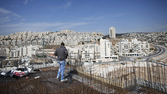 A labourer stands on an apartment building under construction in a Jewish settlement known to Israelis as Har Homa and to Palestinians as Jabal Abu Ghneim, in an area of the West Bank that Israel captured in a 1967 war and annexed to the city of Jerusalem, October 28, 2014. (Reuters/Ronen Zvulun)
