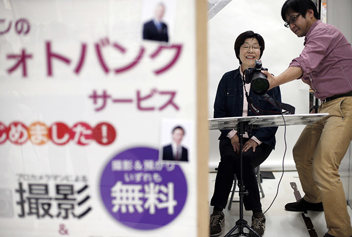 A woman smiles as she is shown her photographic portrait which will be used at her funeral during an end-of-life seminar held by Japan's largest retailer Aeon Co in Tokyo October 24, 2014. (Reuters/Toru Hanai)