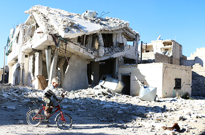 A Syrian boy rides his bike past a destroyed building in the northern Syrian city of Aleppo (AFP Photo / Baraa Al-Halabi)