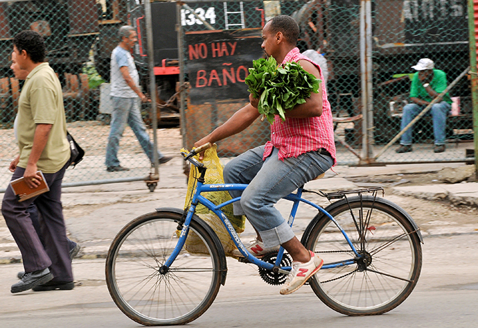 A man carries vegetables as he rides his bike in Havana (AFP Photo / Yamil Lage)