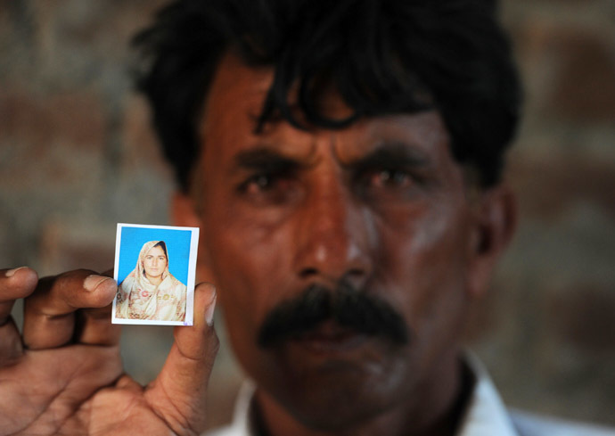 Pakistani resident Mohammad Iqbal poses for a photograph as he holds up an image of his wife Farzana Parveen, who was beaten to death with bricks by her father and other family members for marrying a man of her own choice, in Chak 367 some 40 kms from Faisalabad on May 30, 2014. (AFP Photo)