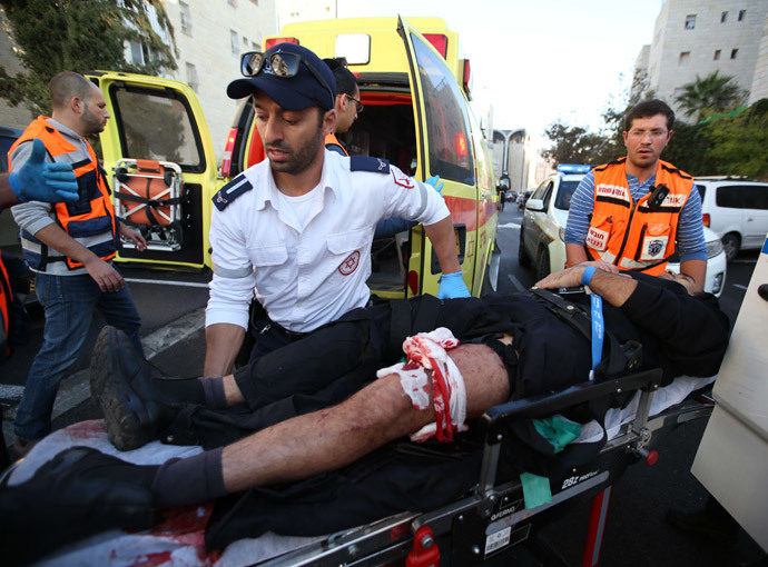 An Israeli man that was injured in an attack, by two Palestinians on Israeli worshippers at a synagogue, is taken to an ambulance by emergency personnel in the ultra-Orthodox Har Nof neighbourhood in Jerusalem on November 18, 2014. (AFP Photo / Miri Tsachie)