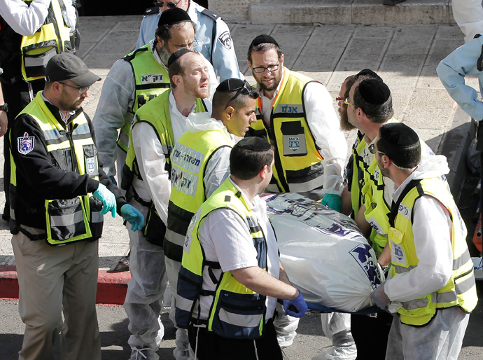 Israeli emergency services members carry a body at the scene of an attack, by two Palestinians, on Israeli worshippers at a synagogue in the ultra-Orthodox Har Nof neighbourhood in Jerusalem on November 18, 2014. (AFP Photo / Ahmad Gharabli)