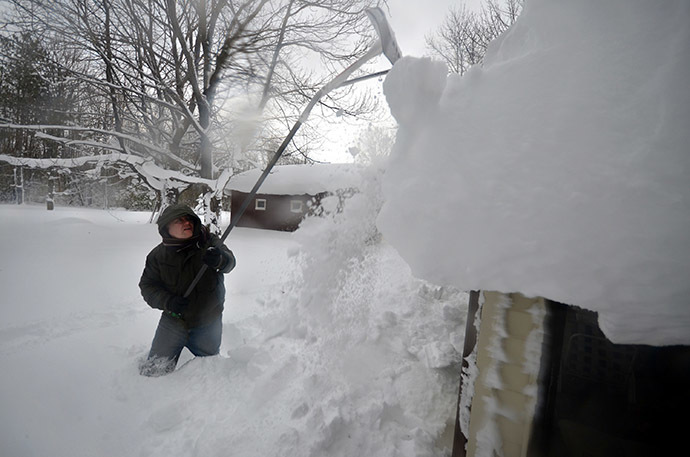 Mike Ostrander tries to remove some of the five feet of snow from his roof on November 20, 2014 in the Lakeview neighborhood of Buffalo, New York. (AFP Photo/John Normile)