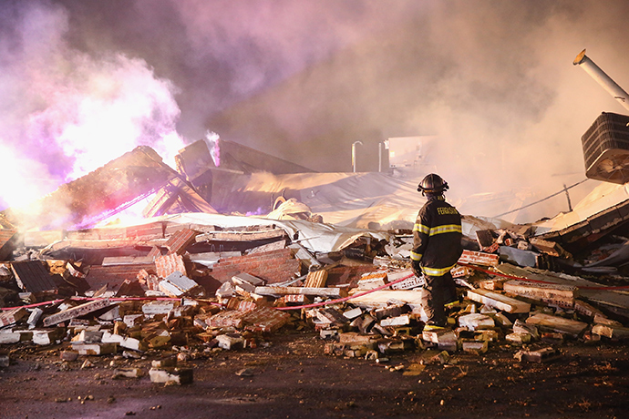 A Ferguson firefighter surveys damage to a strip mall that was set on fire when rioting erupted following the grand jury announcement in the Michael Brown case on November 25, 2014 in Ferguson, Missouri (AFP Photo / Scott Olson)