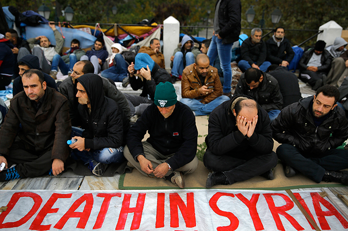 Syrian refugees, some with tape across their mouths, sit with a banner during a protest for a sixth consecutive day in central Athens November 24, 2014 (Reuters / Yannis Behrakis)