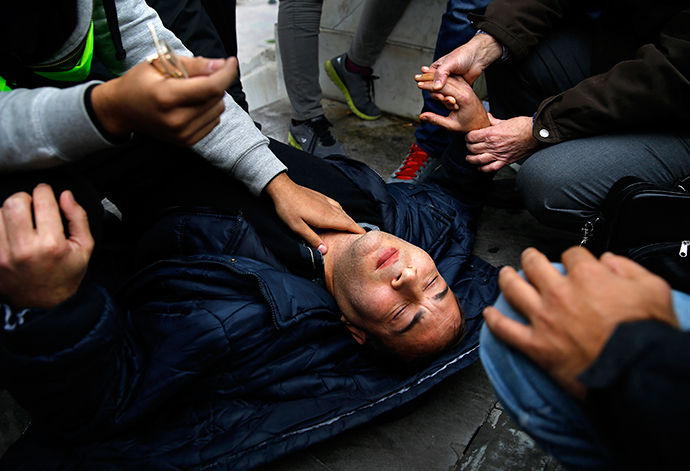 A Syrian refugee is tended to by fellow refugees after collapsing during a protest on its sixth consecutive day in central Athens November 24, 2014 (Reuters / Yannis Behrakis)